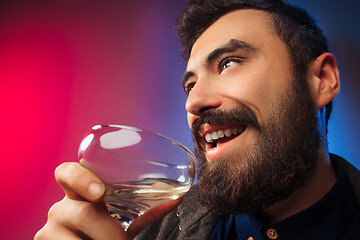 Image showing The surprised young man posing with glass of wine.