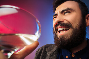 Image showing The surprised young man posing with glass of wine.