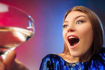 Image showing The surprised young woman in party clothes posing with glass of wine.