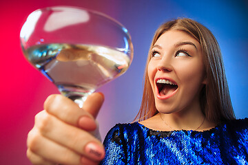 Image showing The surprised young woman in party clothes posing with glass of wine.