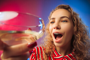 Image showing The surprised young woman in party clothes posing with glass of wine.