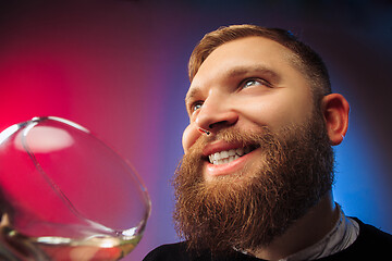 Image showing The surprised young man posing with glass of wine.