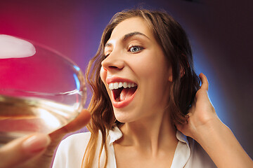 Image showing The surprised young woman in party clothes posing with glass of wine.