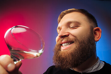 Image showing The surprised young man posing with glass of wine.