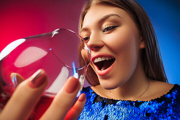 Image showing The surprised young woman in party clothes posing with glass of wine.