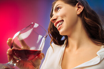 Image showing The surprised young woman in party clothes posing with glass of wine.