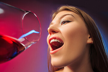 Image showing The surprised young woman in party clothes posing with glass of wine.