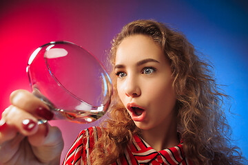 Image showing The surprised young woman in party clothes posing with glass of wine.