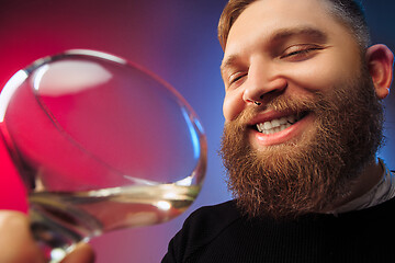 Image showing The surprised young man posing with glass of wine.