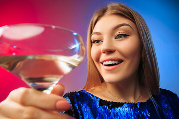 Image showing The surprised young woman in party clothes posing with glass of wine.