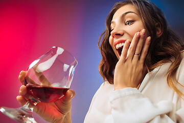 Image showing The surprised young woman in party clothes posing with glass of wine.