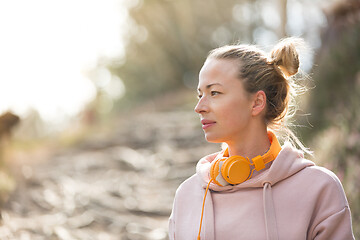 Image showing Portrait of beautiful sports woman with hoodie and headphones during outdoors training session.