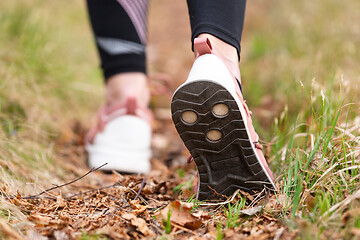 Image showing Rear close up view of female step on nature track. Young woman hiking in nature. Adventure, sport and exercise concept