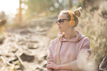 Image showing Portrait of beautiful sports woman wearing sunglasses, hoodie and headphones during outdoors training session