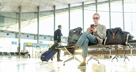 Image showing Woman stucked at airport terminal over flight cancellation writes message to family, sitting in almost empty airport terminal due to coronavirus pandemic, Covid 19, outbreak travel restrictions