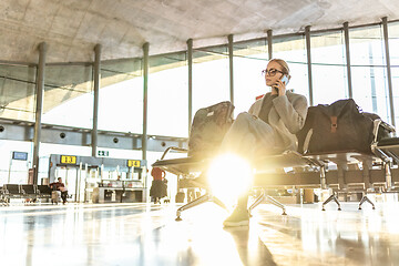 Image showing Woman stucked at airport terminal over flight cancellation,calling family, sitting in almost empty airport terminal due to coronavirus pandemic, Covid 19, outbreak travel restrictions