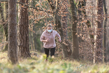 Image showing Corona virus, or Covid-19, is spreading all over the world. Portrait of caucasian sporty woman wearing a medical protection face mask while running in nature.