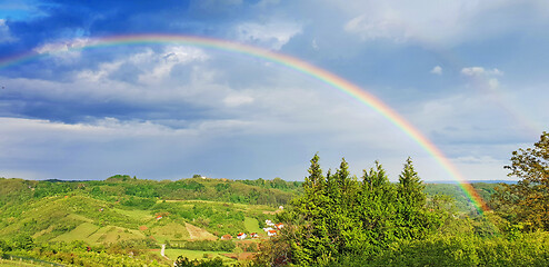 Image showing Spring rural rainbow landscape, view of green meadows and hills