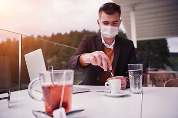 Image showing man in restaurant drinking coffee wearing face mask