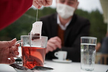 Image showing couple with protective medical mask  having coffee break in a re