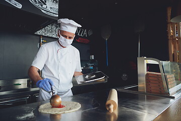 Image showing chef  with protective coronavirus face mask preparing pizza