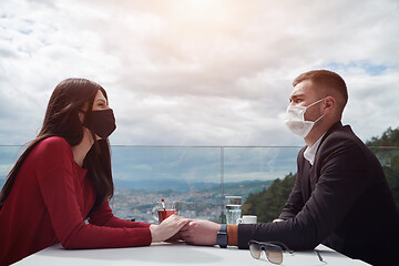 Image showing couple with protective medical mask  having coffee break in a re