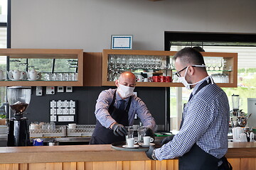 Image showing waiter in a medical protective mask serves  the coffee in restau