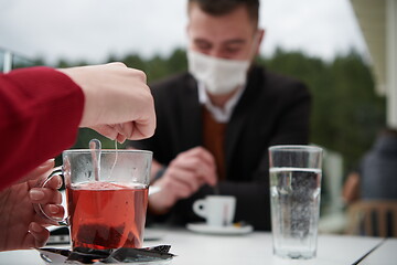 Image showing couple with protective medical mask  having coffee break in a re