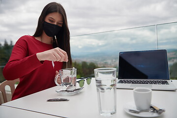 Image showing woman in restaurant drinking tea wearingmedical  face mask