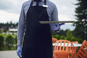 Image showing waiter in a medical protective mask serves  the coffee in restau