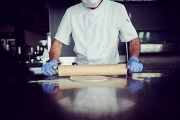 Image showing chef  with protective coronavirus face mask preparing pizza