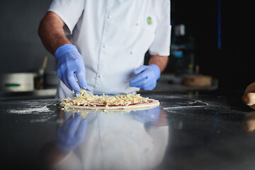 Image showing chef  with protective coronavirus face mask preparing pizza