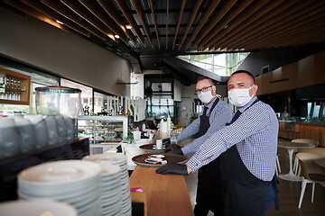 Image showing waiter in a medical protective mask serves  the coffee in restau