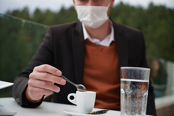 Image showing man in restaurant drinking coffee wearing face mask