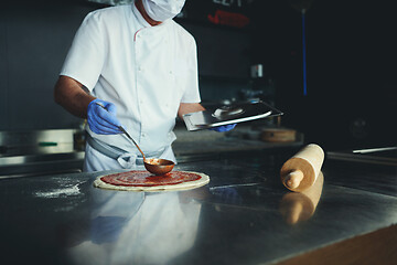 Image showing chef  with protective coronavirus face mask preparing pizza