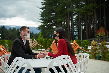 Image showing couple with protective medical mask  having coffee break in a re