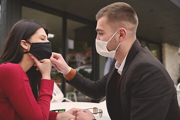 Image showing couple with protective medical mask  having coffee break in a re