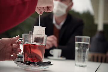 Image showing couple with protective medical mask  having coffee break in a re