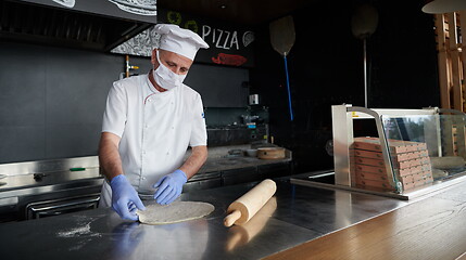 Image showing chef  with protective coronavirus face mask preparing pizza