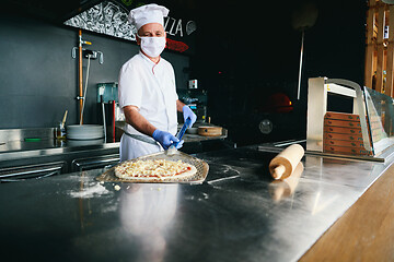 Image showing chef  with protective coronavirus face mask preparing pizza