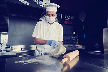 Image showing chef  with protective coronavirus face mask preparing pizza