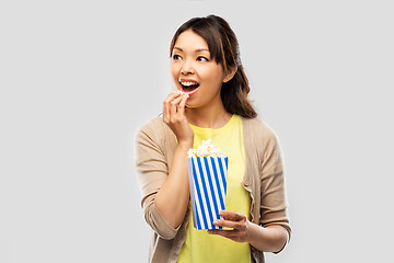Image showing smiling asian woman eating popcorn