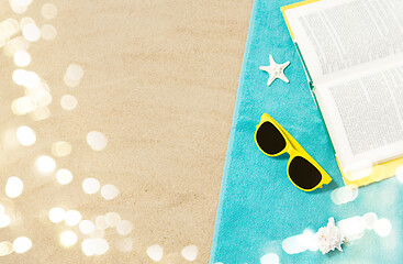 Image showing sunglasses and book on beach towel on sand