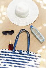 Image showing beach bag, sunscreen, sunglasses and hat on sand