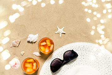 Image showing cocktails, sun hat and sunglasses on beach sand