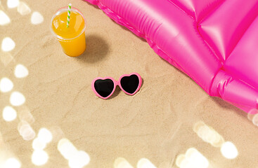 Image showing sunglasses, juice and pool mattress on beach sand