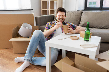 Image showing smiling man eating takeaway food at new home