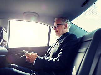 Image showing senior businessman texting on smartphone in car