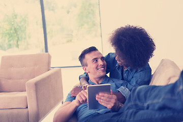 Image showing multiethnic couple relaxing at  home with tablet computers