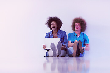 Image showing multiethnic couple sitting on the floor with a laptop and tablet